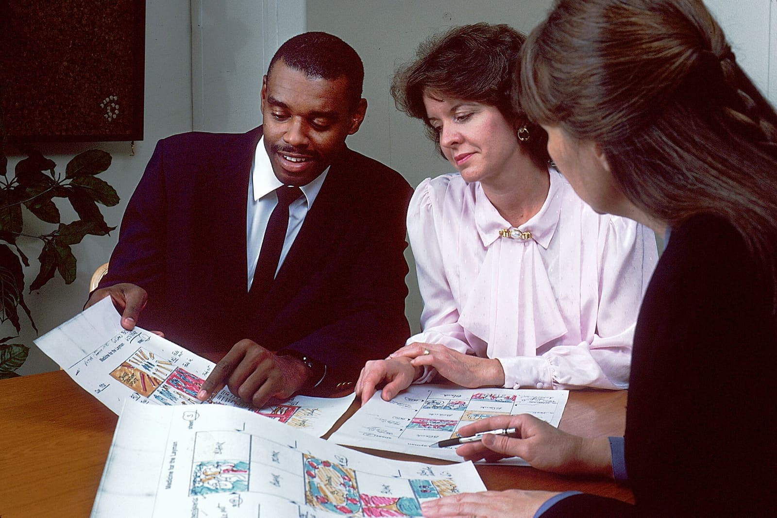 Three colleagues review illustrated storyboards around a conference table