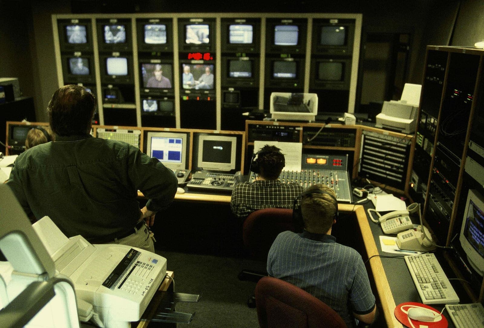 Production workers studying a bank of studio monitors